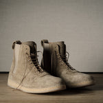 Pair of brown suede boots on a wooden floor with a neutral background