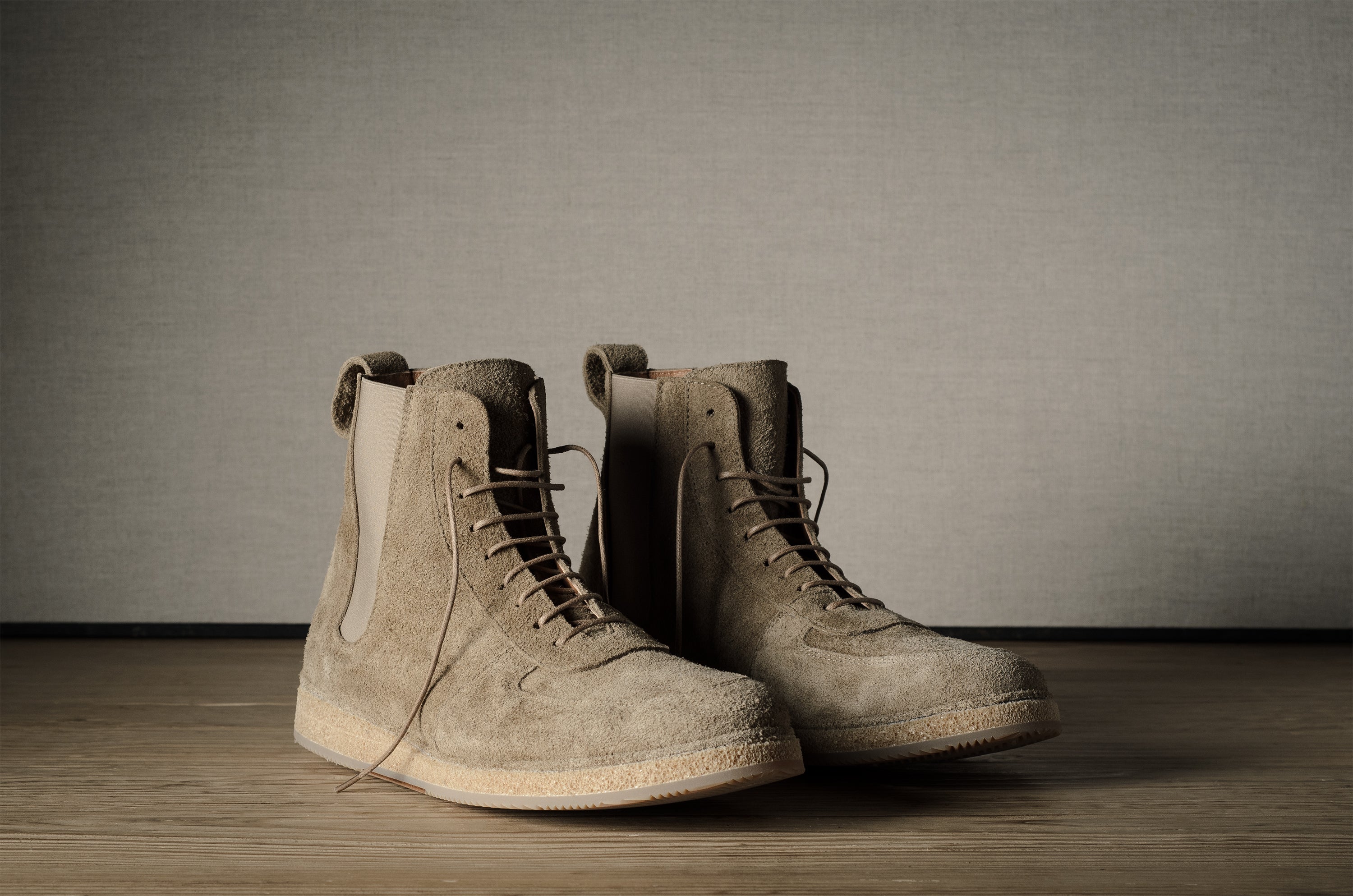 Pair of brown suede boots on a wooden floor with a neutral background