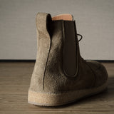 Brown suede boot on a wooden floor with a neutral background