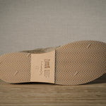 Close-up of a shoe sole with brand label on a wooden floor.