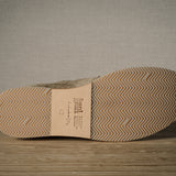 Close-up of a shoe sole with brand label on a wooden floor.