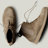 Pair of brown suede boots on a light gray background