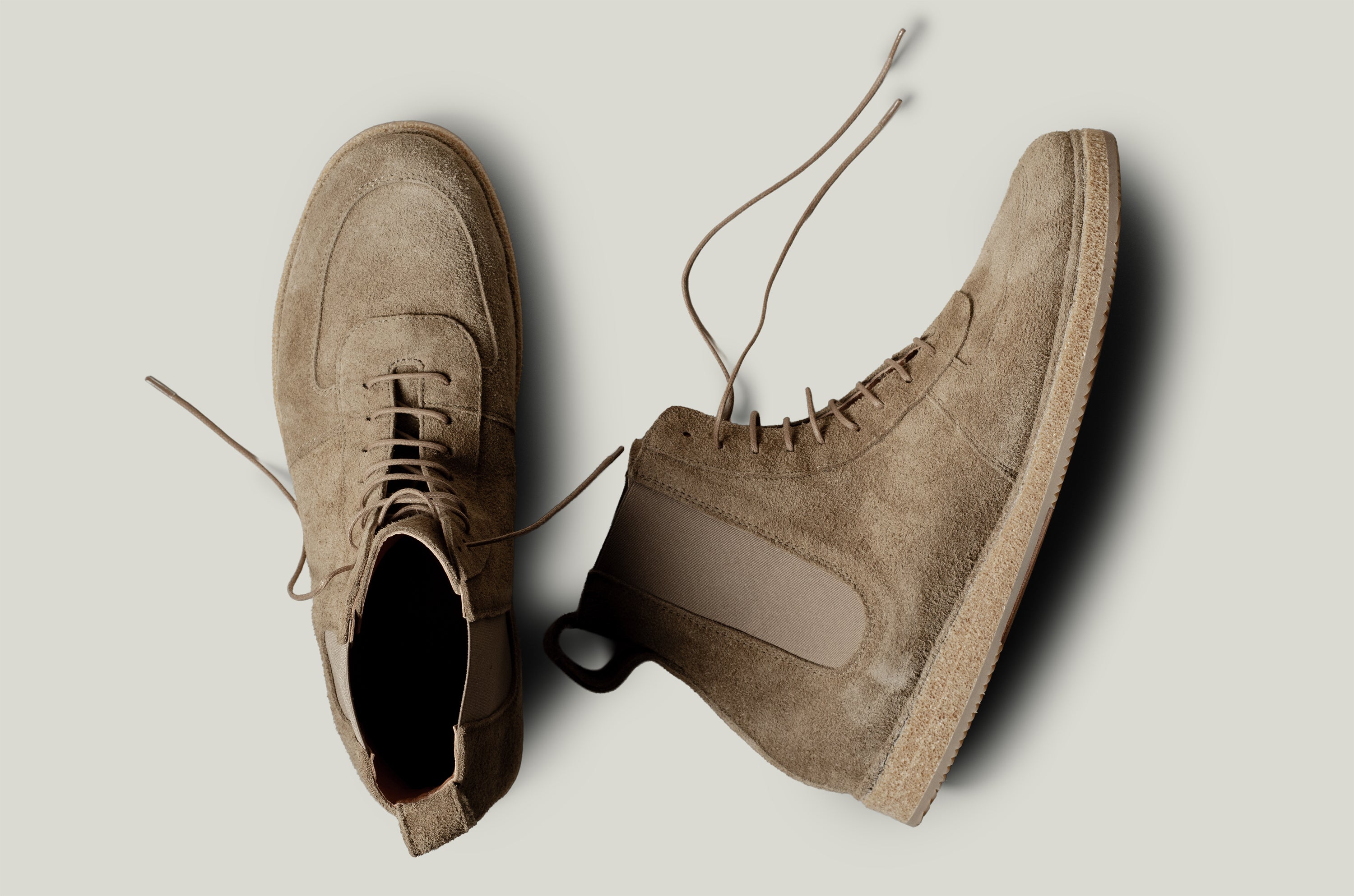 Pair of brown suede boots on a light gray background