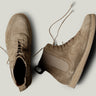 Pair of brown suede boots on a light gray background