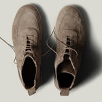 Pair of brown suede boots on a light gray background