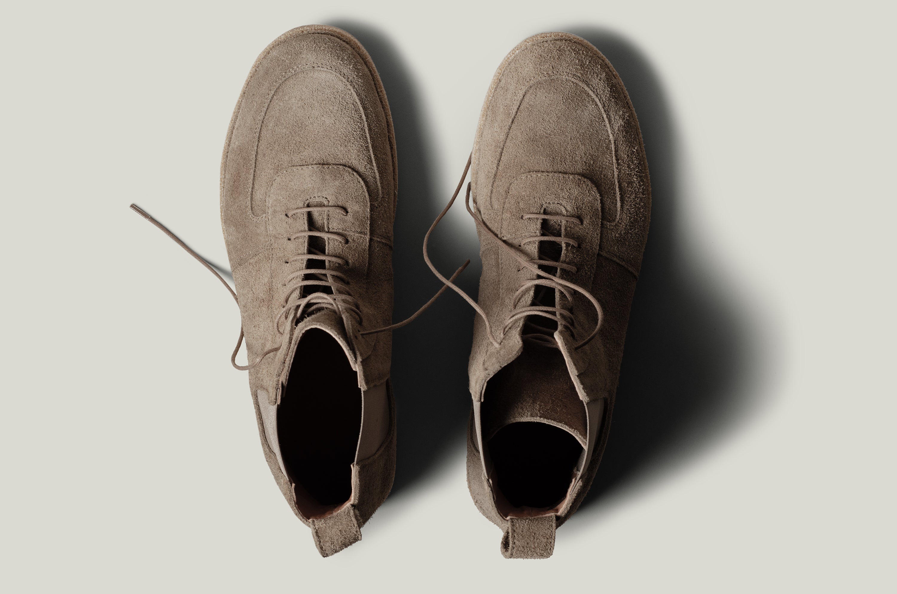 Pair of brown suede boots on a light gray background