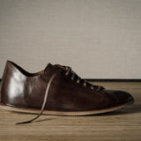 Brown leather shoe on a wooden floor.