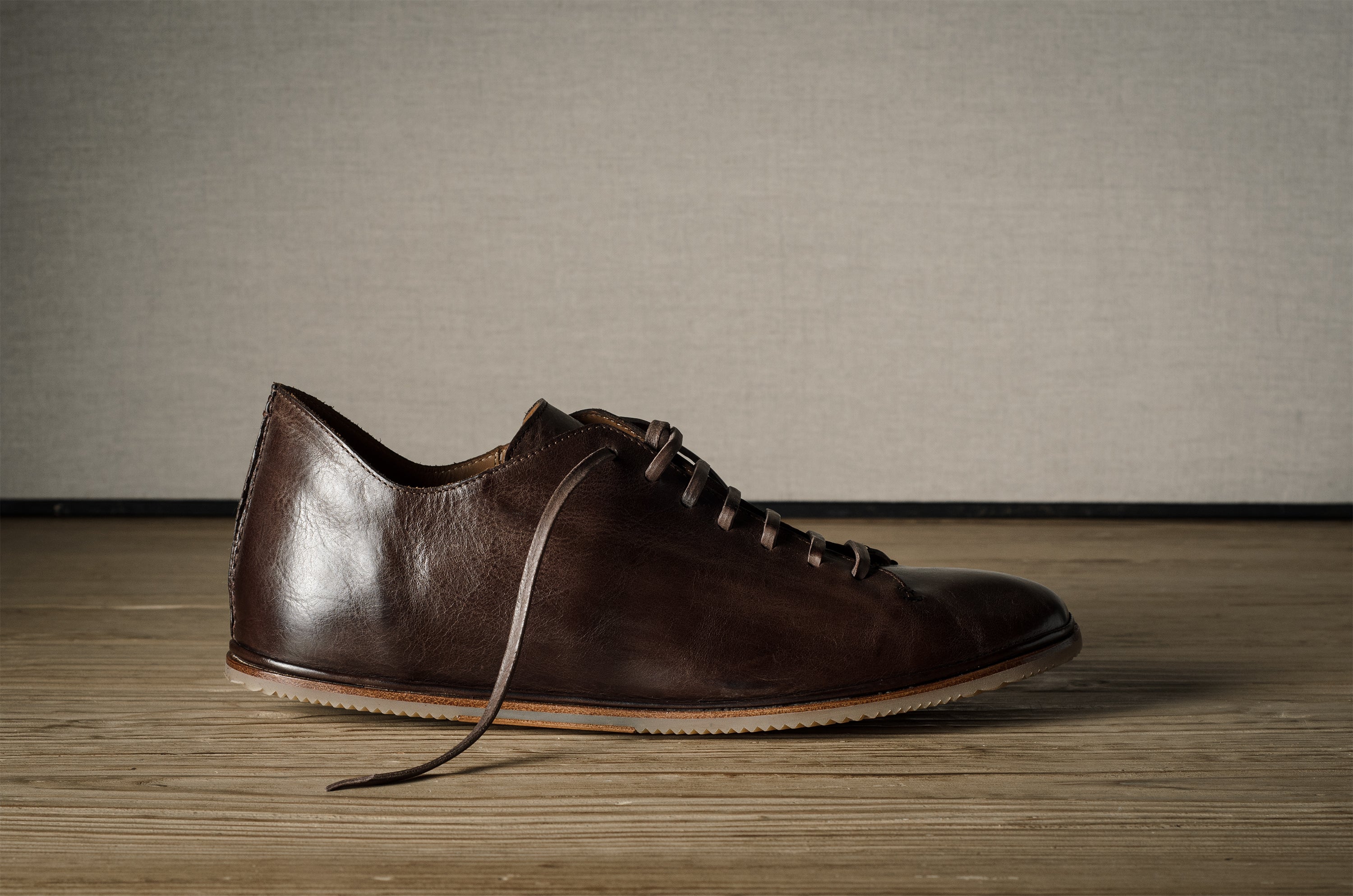 Brown leather shoe on a wooden floor.
