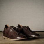 Pair of brown leather shoes on a wooden floor.