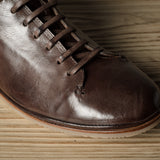 Brown leather shoe on a wooden floor.