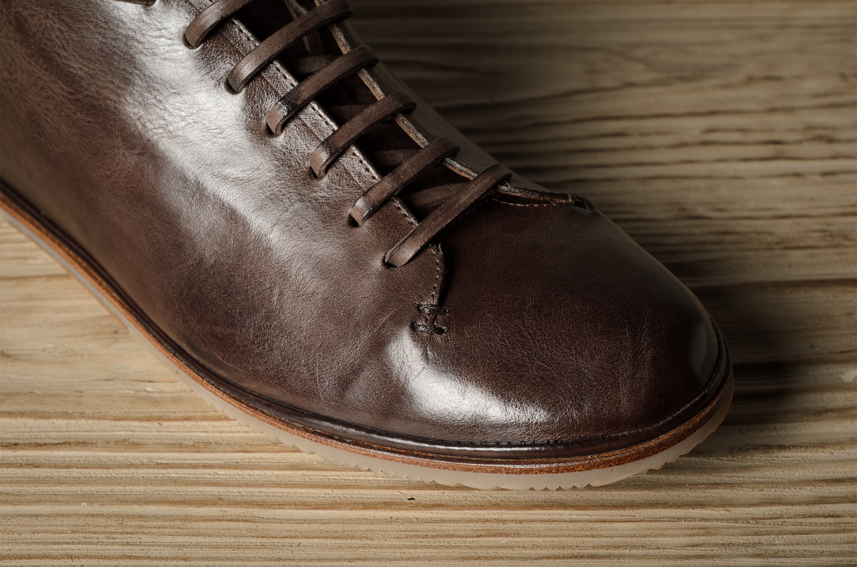 Brown leather shoe on a wooden floor.