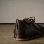 Brown leather shoe on a wooden floor.