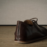 Brown leather shoe on a wooden floor.