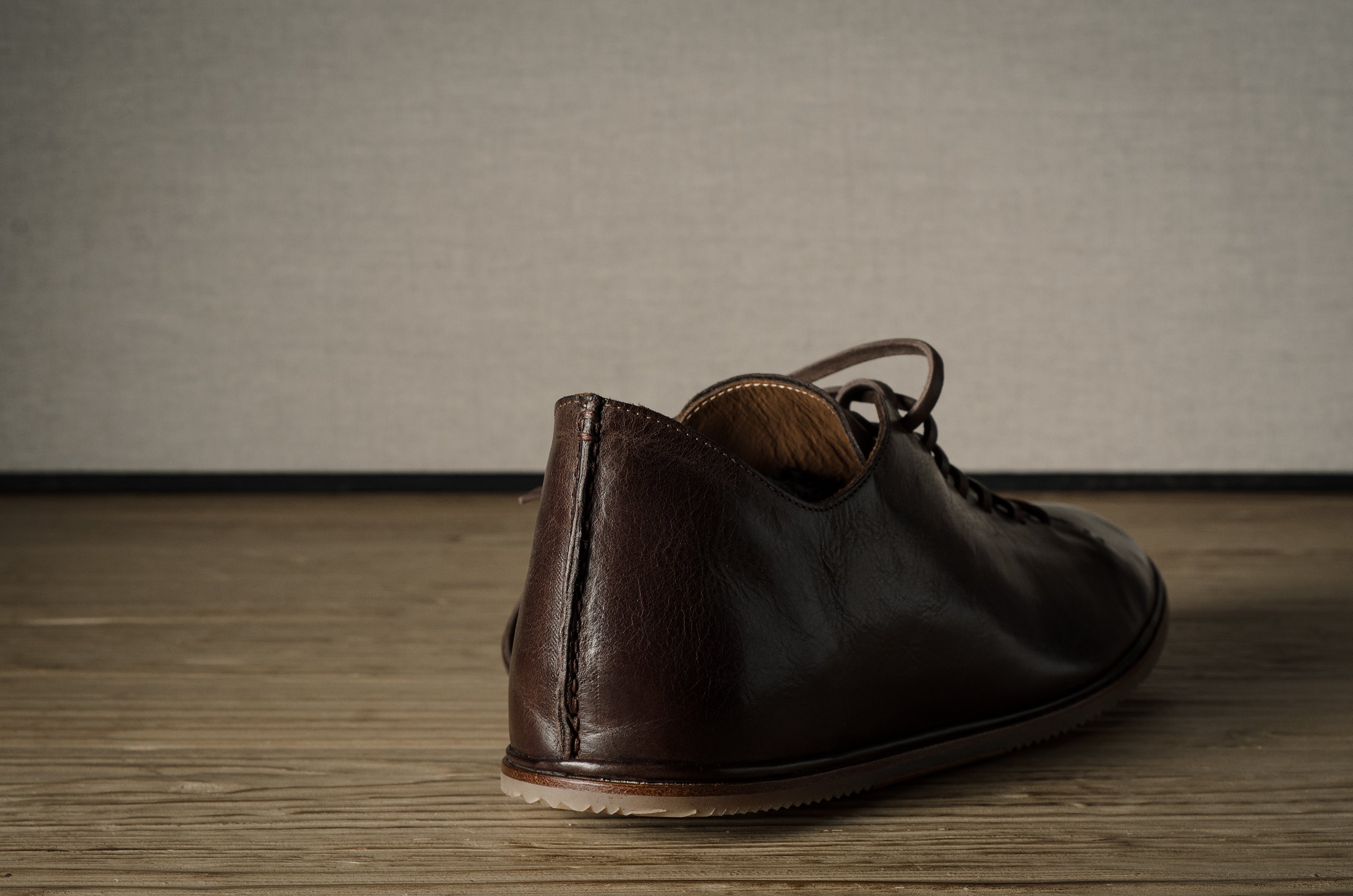 Brown leather shoe on a wooden floor.