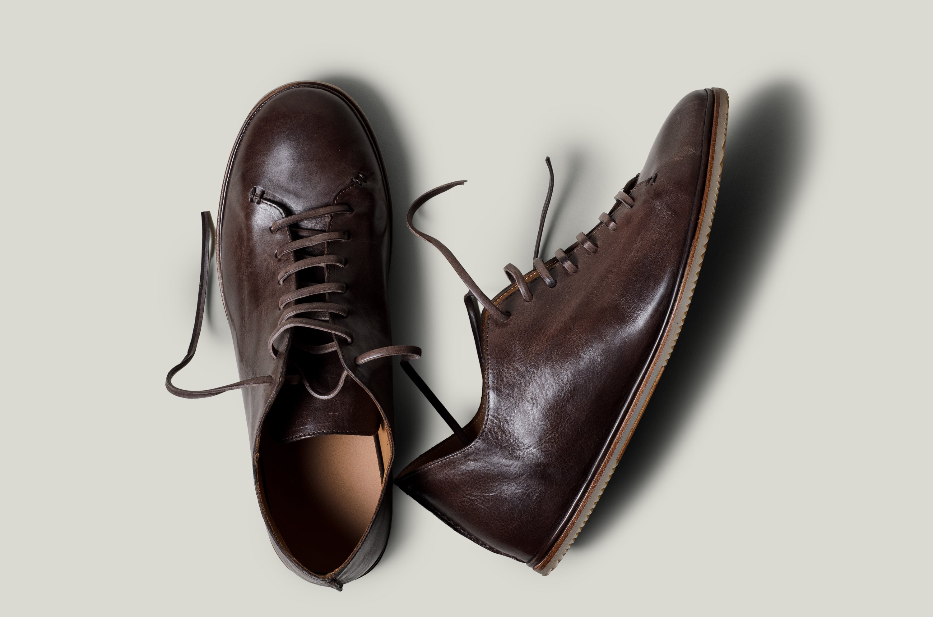 Pair of brown leather shoes on a light gray background
