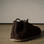 Brown suede shoe on a wooden floor with a neutral background