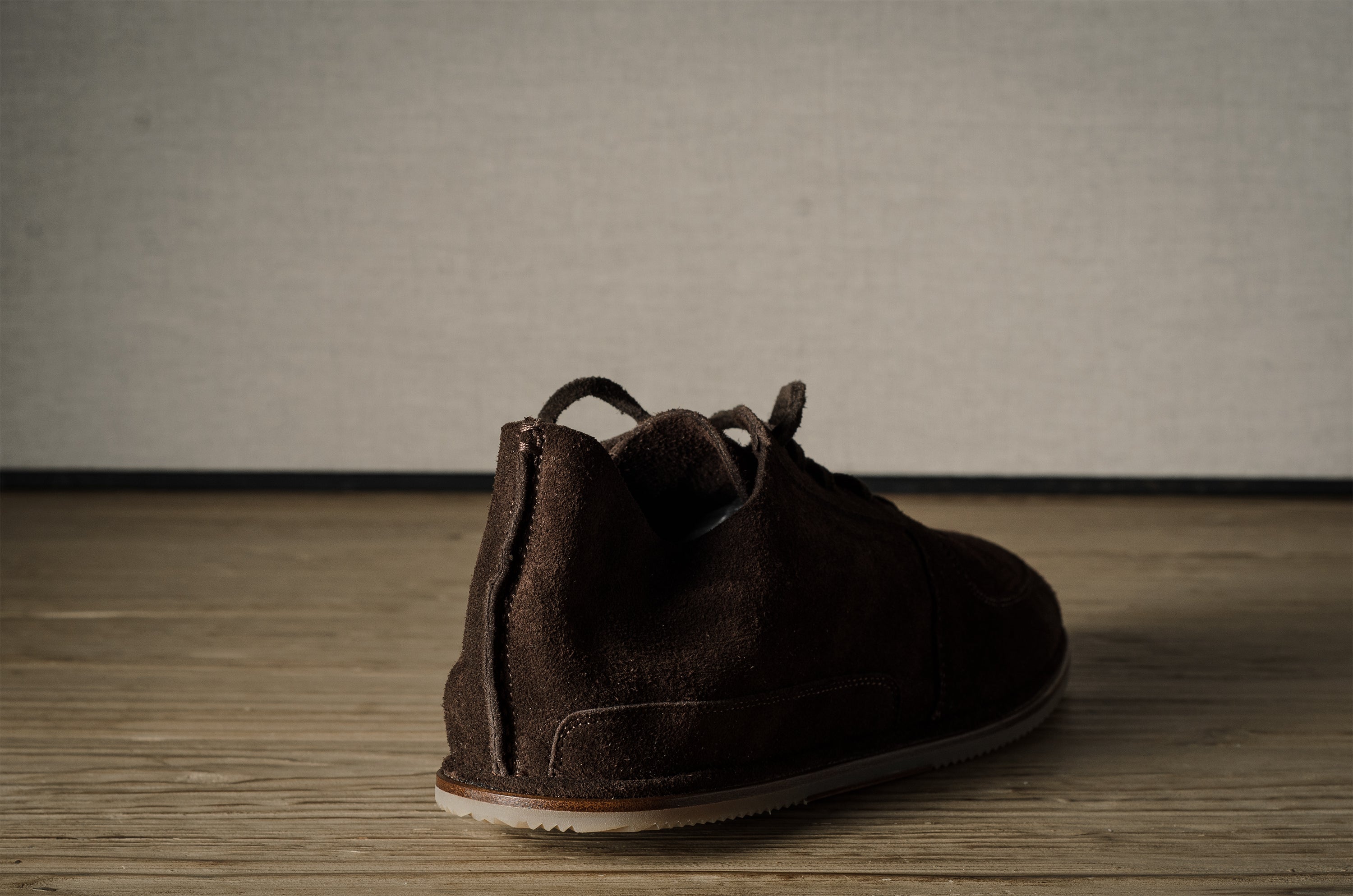 Brown suede shoe on a wooden floor with a neutral background