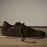 Brown suede shoe on a wooden floor with a neutral background