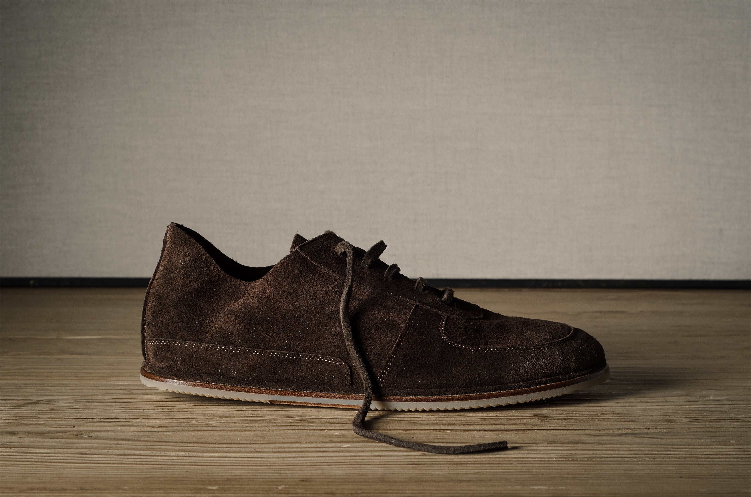 Brown suede shoe on a wooden floor with a neutral background