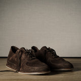 Pair of brown leather shoes on a wooden floor with a neutral background