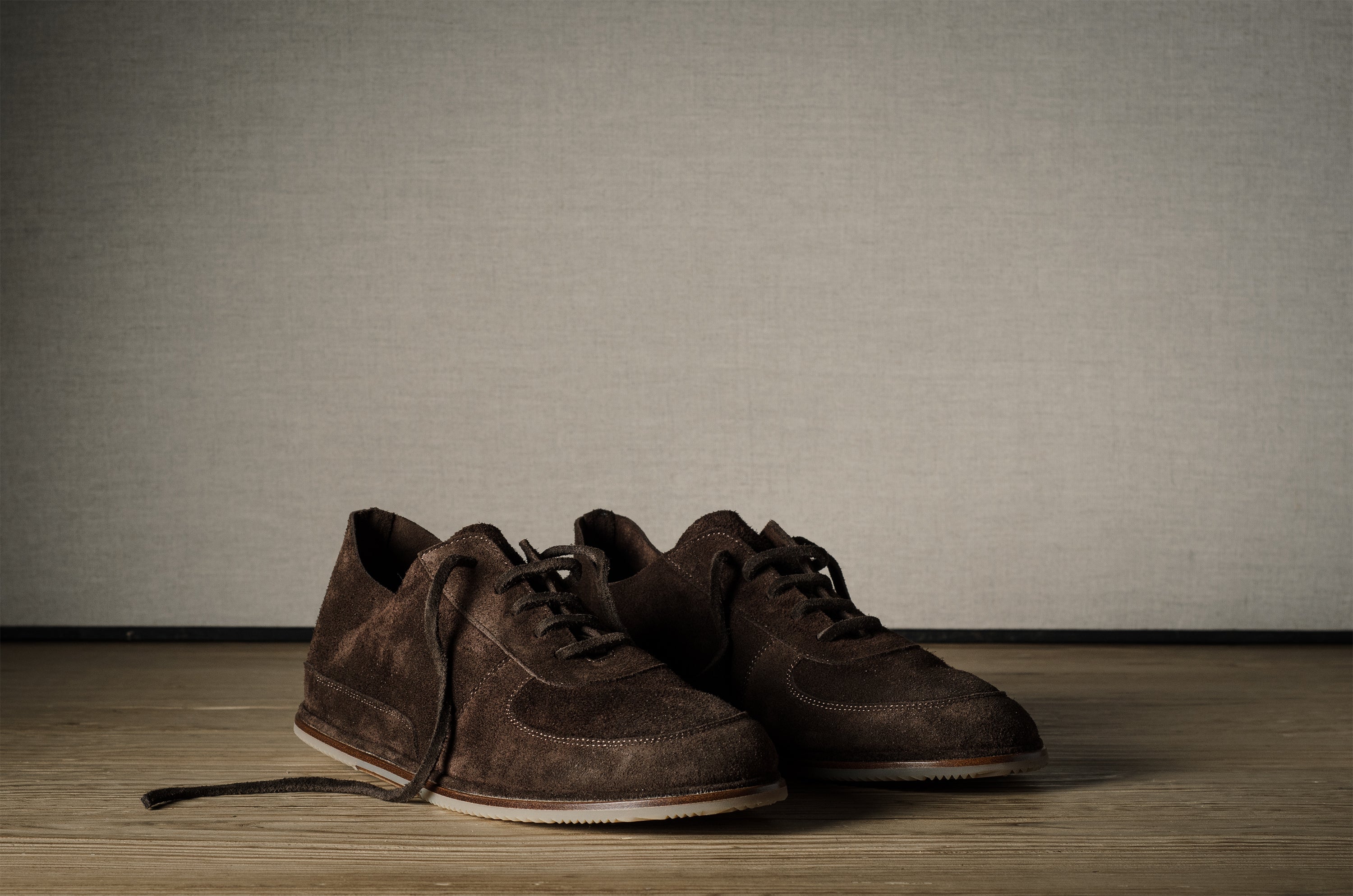 Pair of brown leather shoes on a wooden floor with a neutral background