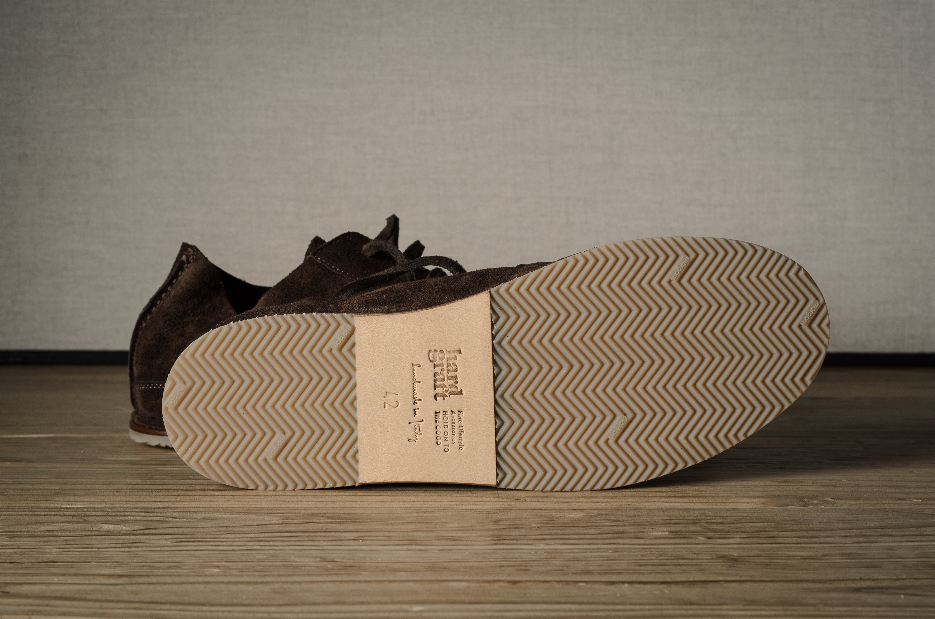 Brown leather shoes with a visible brand label on a wooden floor.