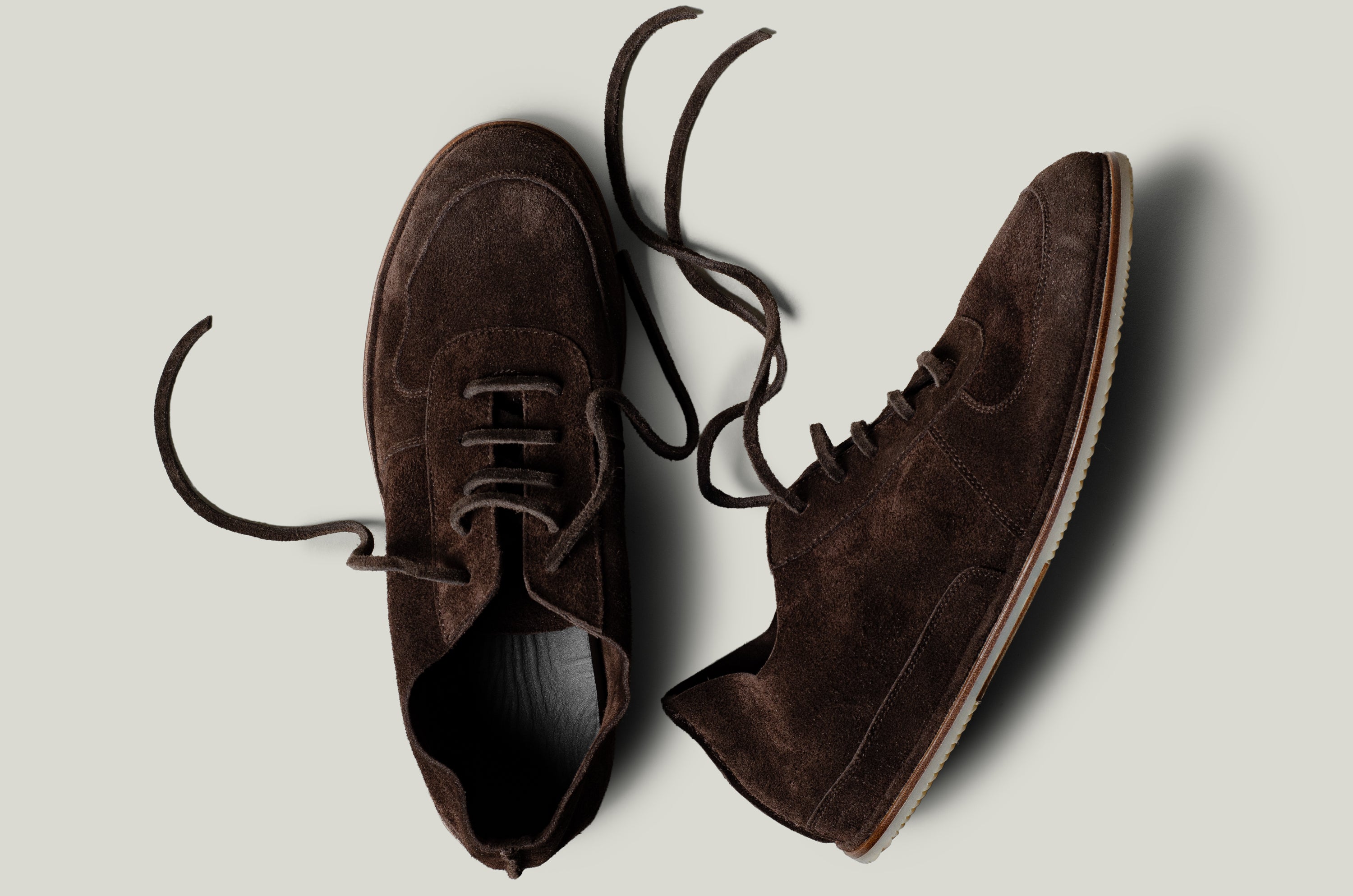 Pair of brown suede shoes on a light gray background
