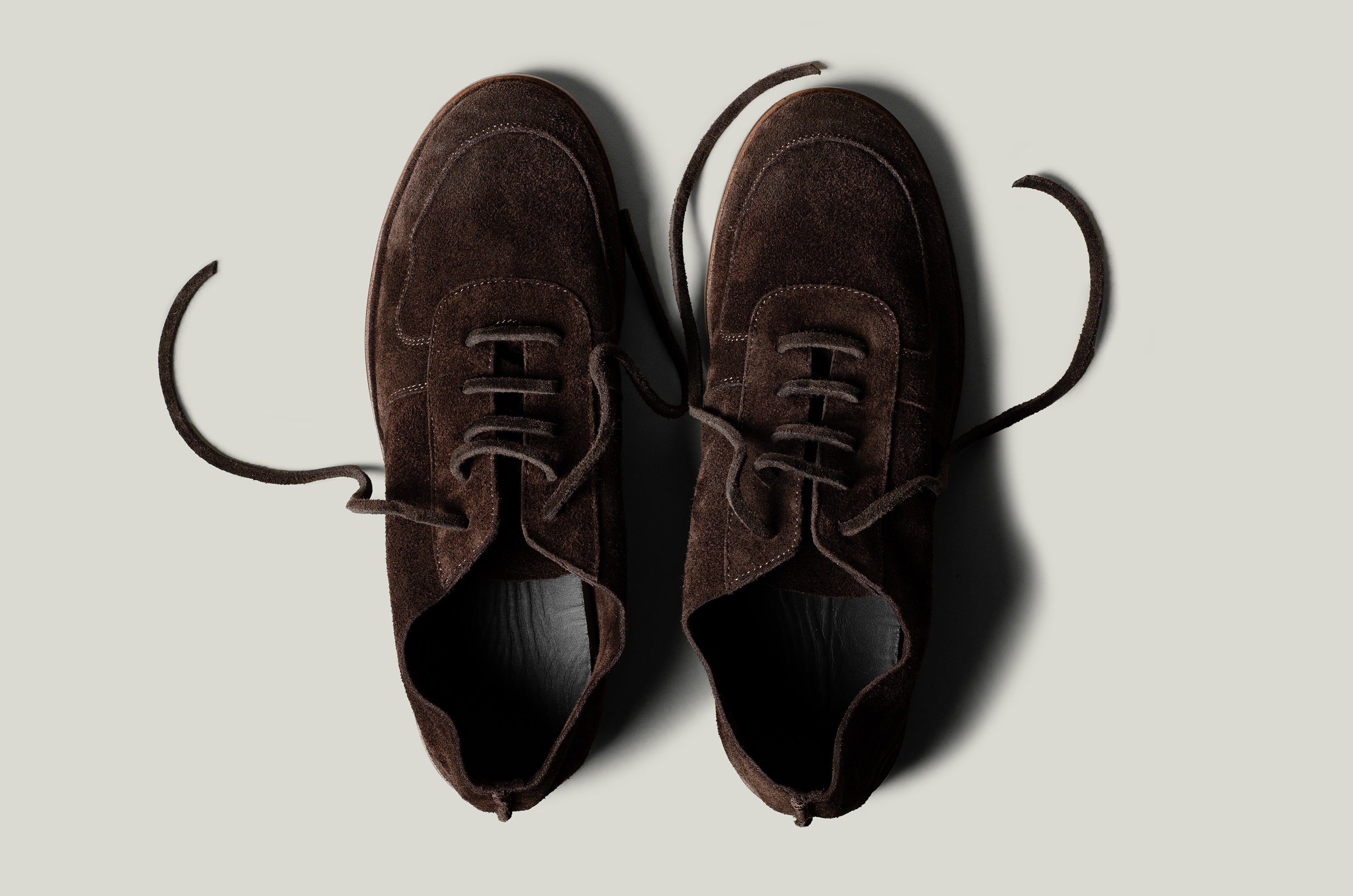 Pair of brown suede shoes on a light gray background