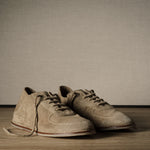 Pair of brown shoes on a wooden floor with a plain background