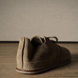 Brown suede shoe on a wooden floor with a neutral background