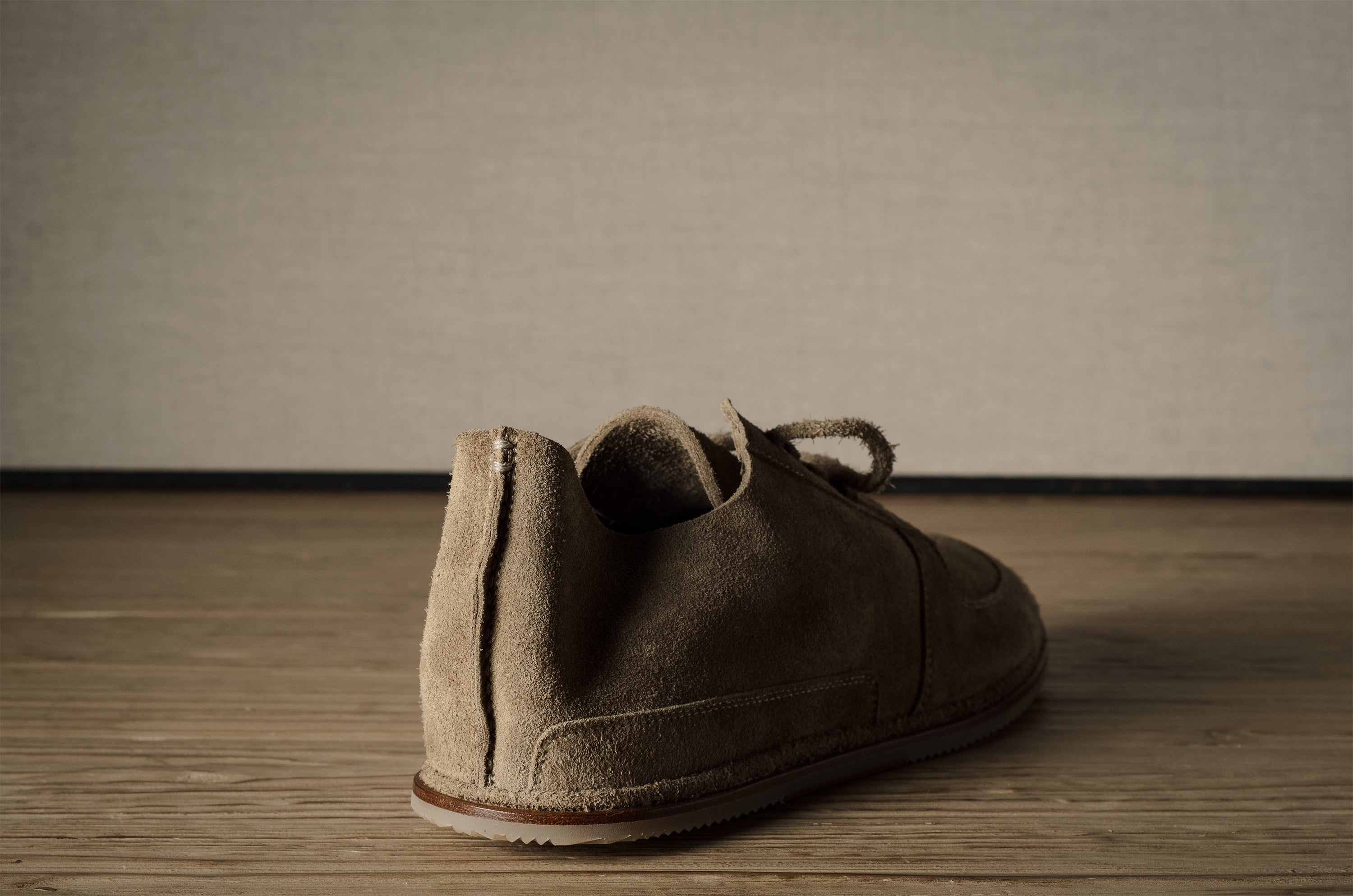 Brown suede shoe on a wooden floor with a neutral background