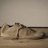 Pair of brown suede shoes on a wooden floor with a neutral background