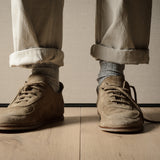 Brown shoes and beige pants on a wooden floor with a neutral background