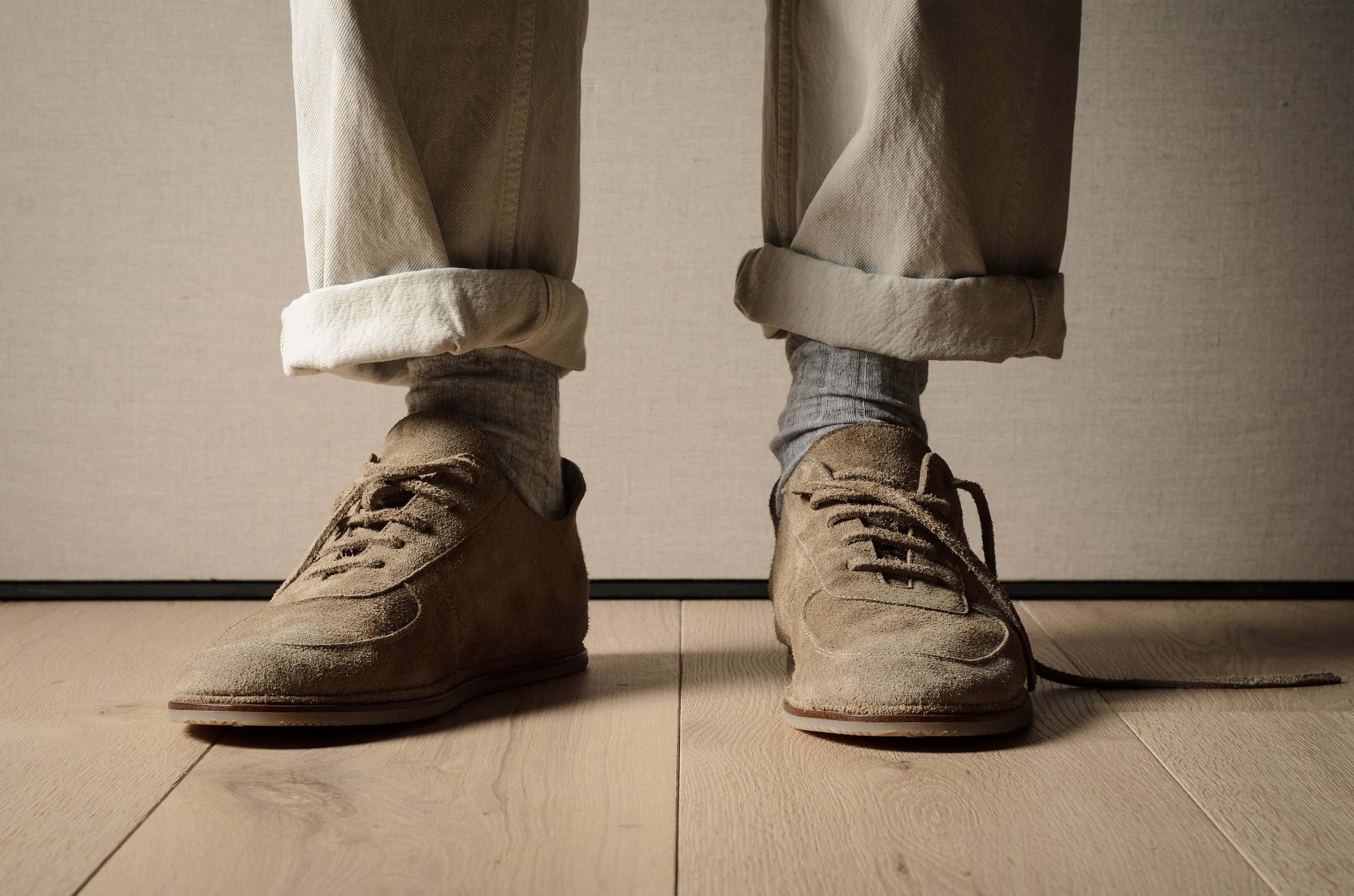 Brown shoes and beige pants on a wooden floor with a neutral background