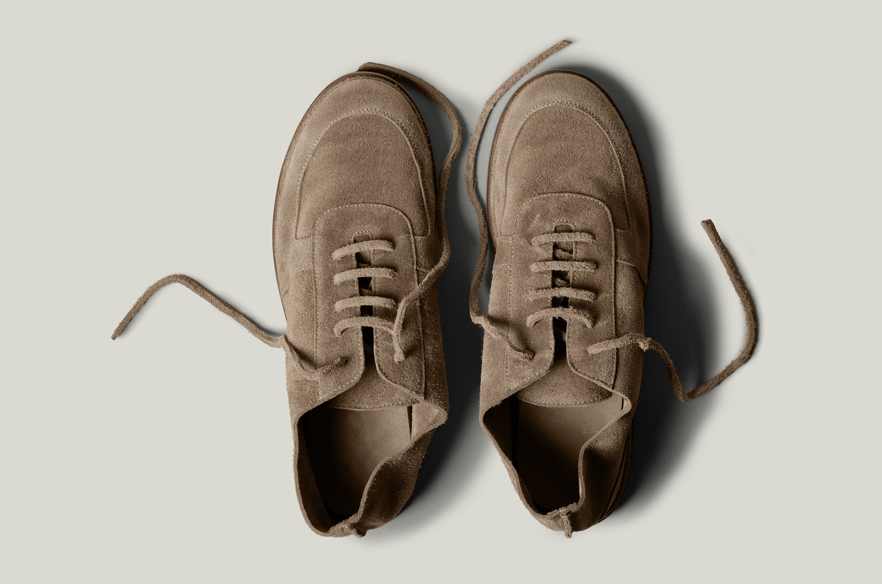 Pair of brown suede shoes on a light gray background
