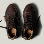 Pair of brown leather sneakers on a light gray background