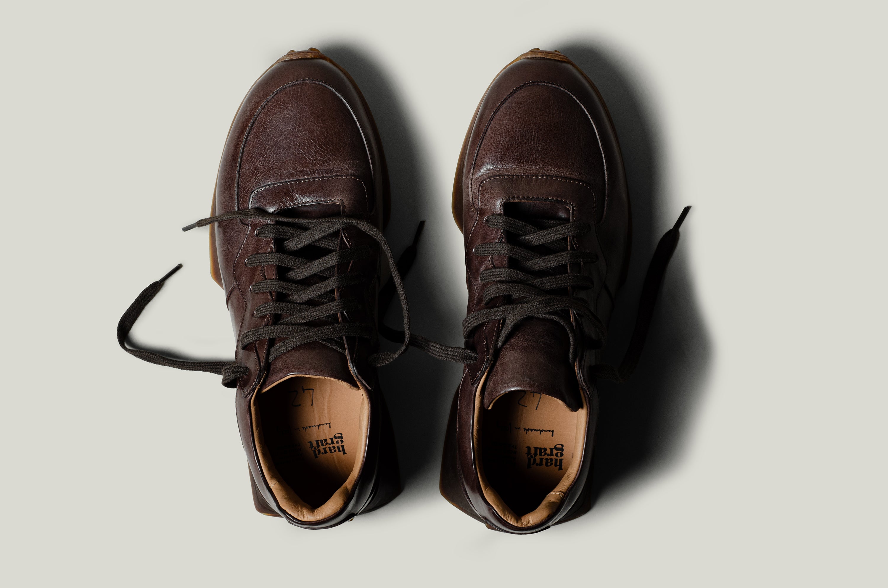 Pair of brown leather sneakers on a light gray background