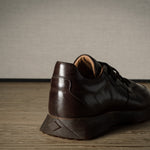 Brown leather sneaker on a wooden floor with a neutral background