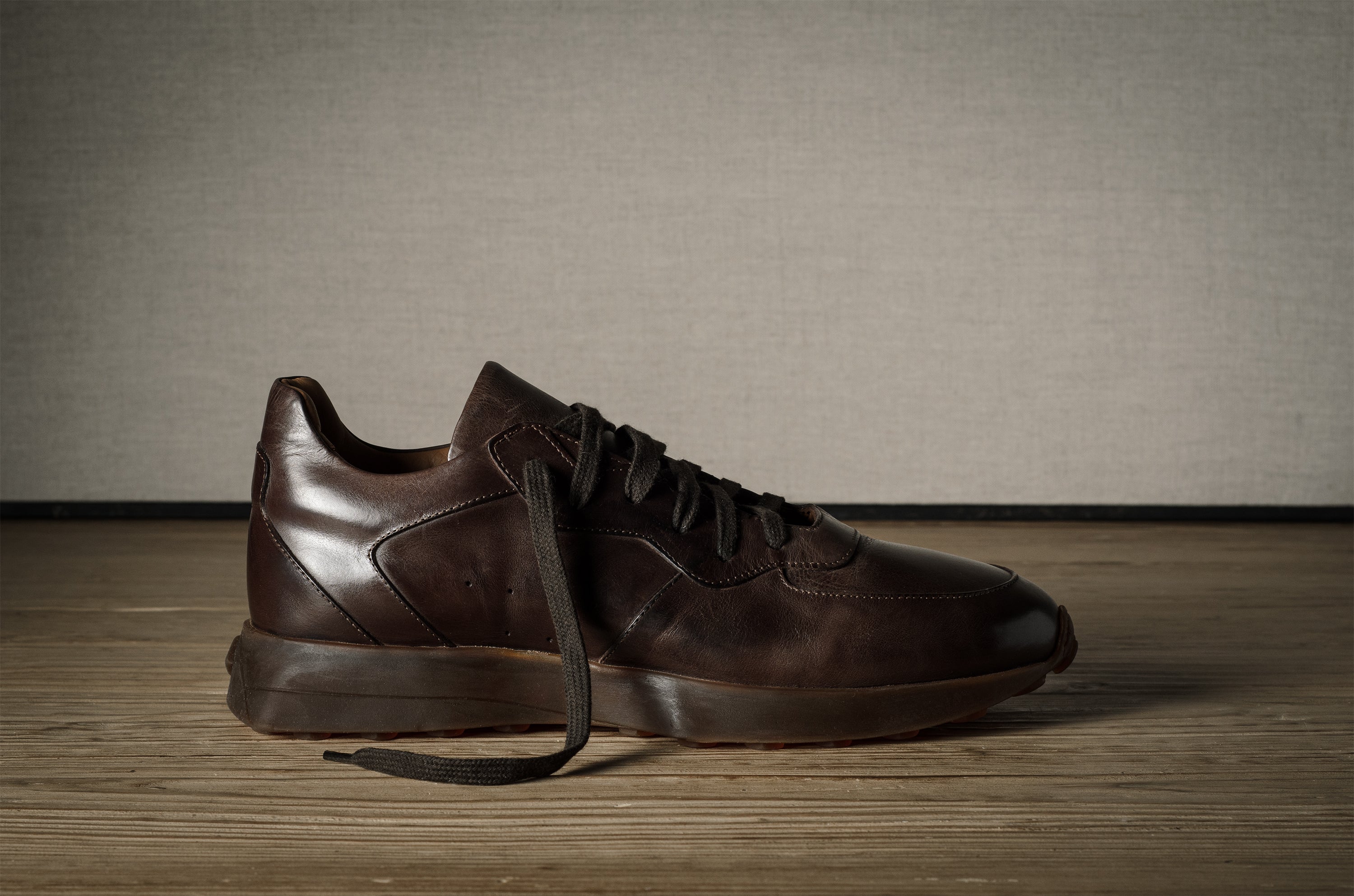 Pair of brown leather sneakers on a wooden floor with a neutral background