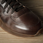 Brown leather sneaker on a wooden surface