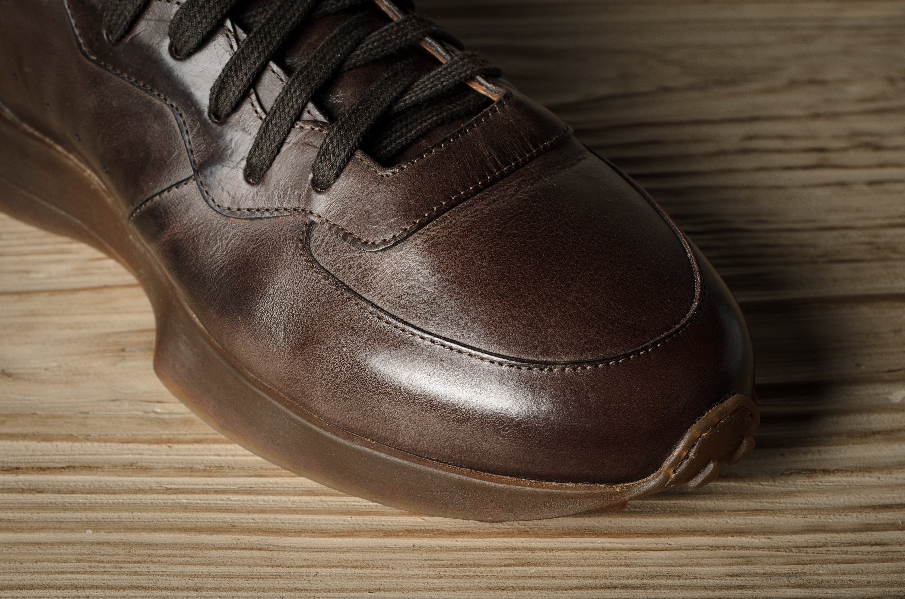 Brown leather sneaker on a wooden surface