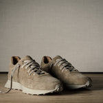 Pair of beige sneakers on a wooden floor with a neutral background