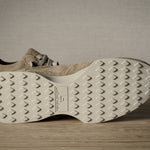 Beige sneakers with textured sole on a wooden floor