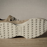 Beige sneakers with textured sole on a wooden floor