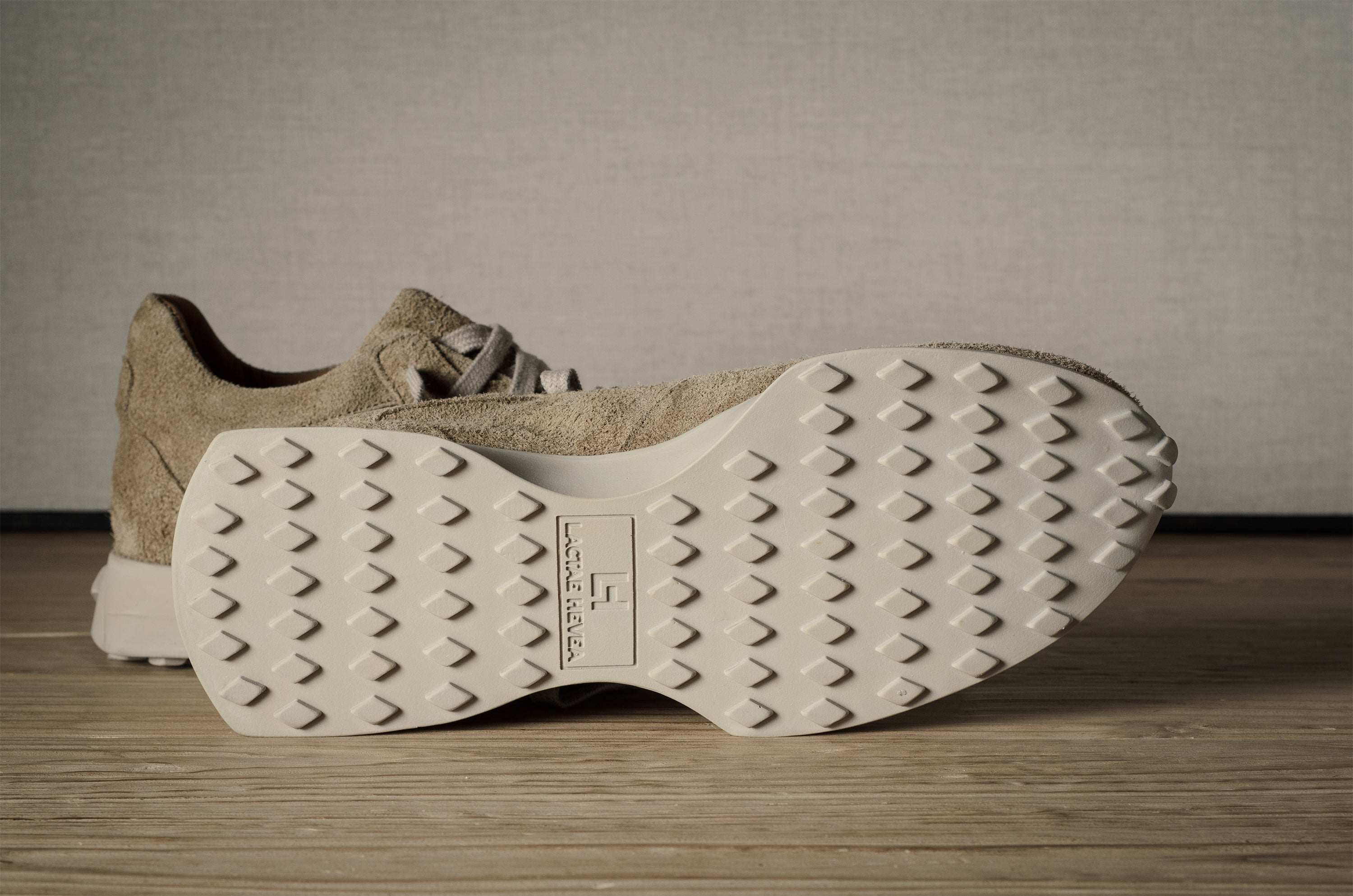 Beige sneakers with textured sole on a wooden floor