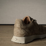 Brown suede sneaker on a wooden floor with a neutral background