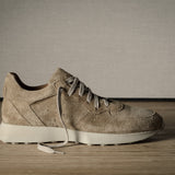 Beige sneaker on a wooden floor with a neutral background