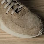 Brown suede sneaker on a wooden surface