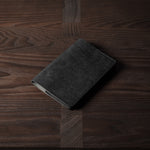 Black leather passport case on a wooden surface