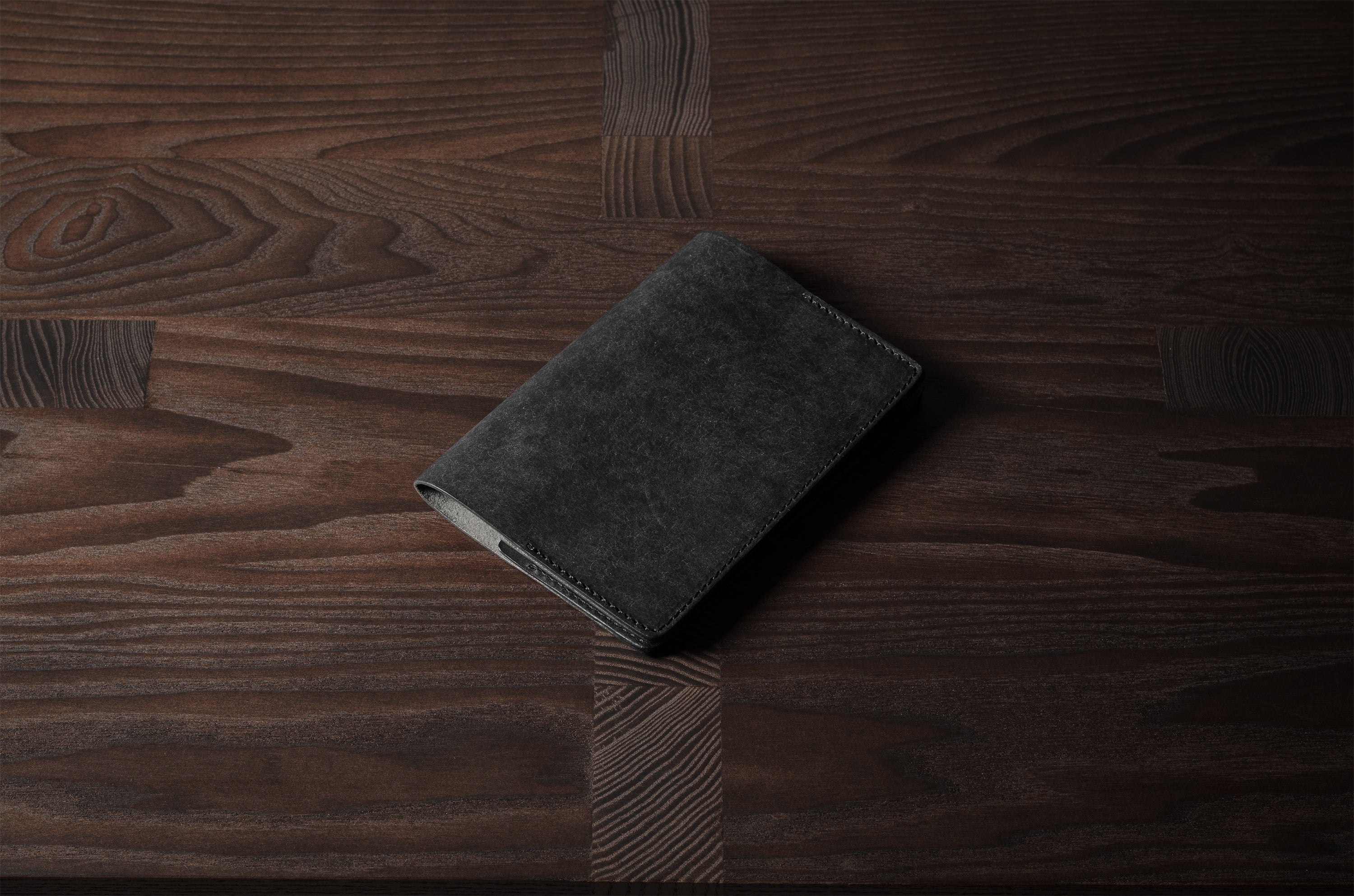Black leather passport case on a wooden surface